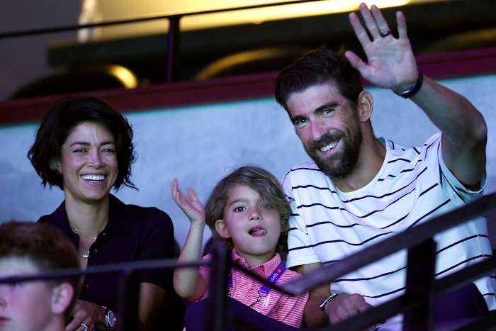 Michael Phelps and his son Boomer, with wife Nicole, wave to the crowd from the stands at the 2021 U.S. Olympic trials in Omaha.